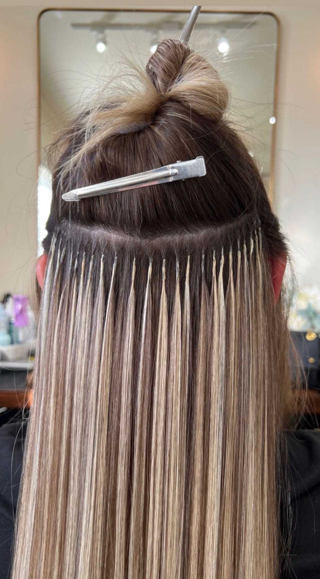 Hair extensions applied in a salon, showing detailed strands and attachment method.