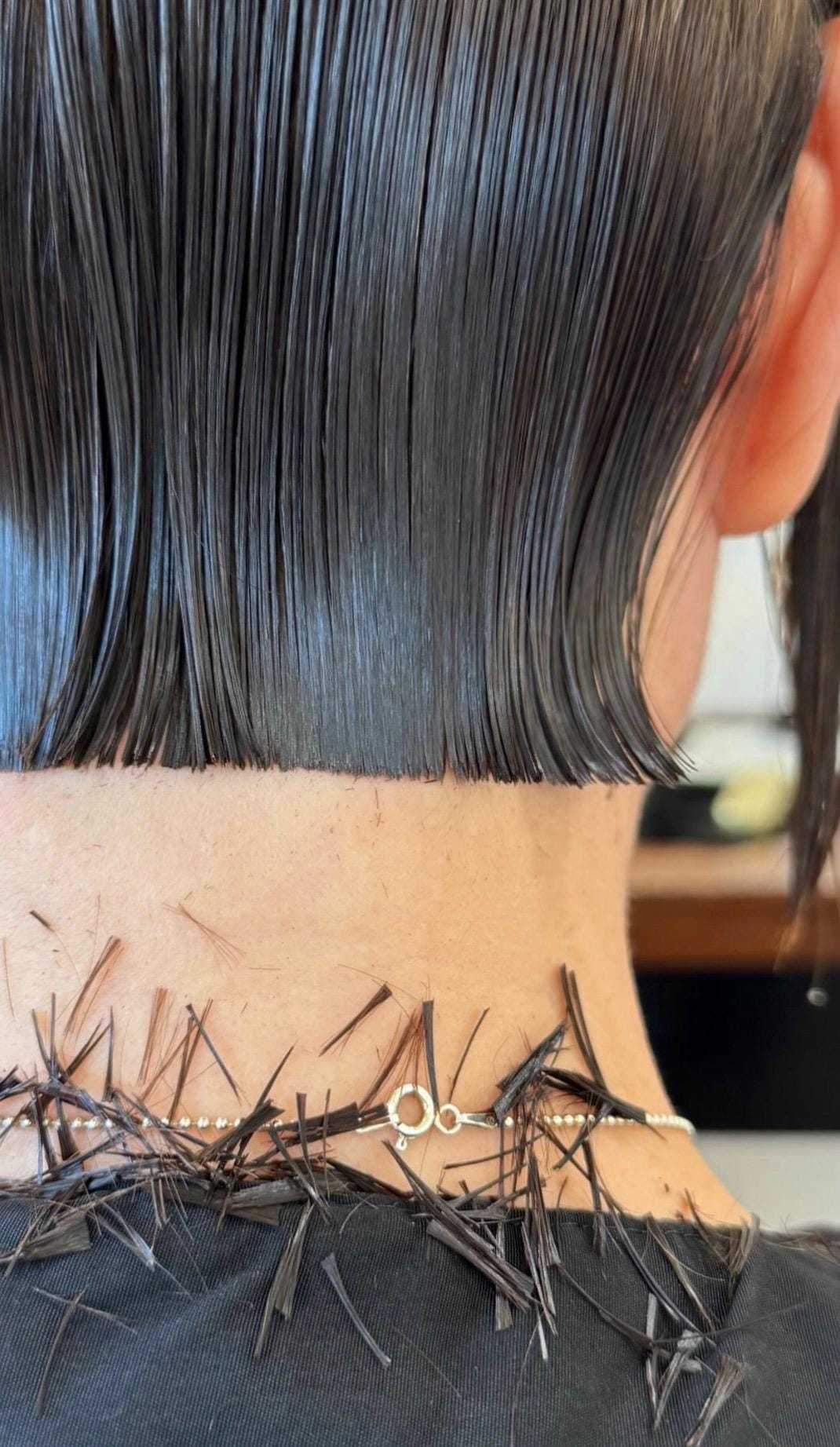 Close-up of a sleek bob haircut with trimmed hair strands on a black cape.